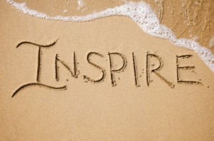 The word Inspire written in the sand. 